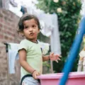 Seorang anak kecil sedang merapikan mainannya sendiri di rumah sebagai bentuk cara membantu anak mandiri
