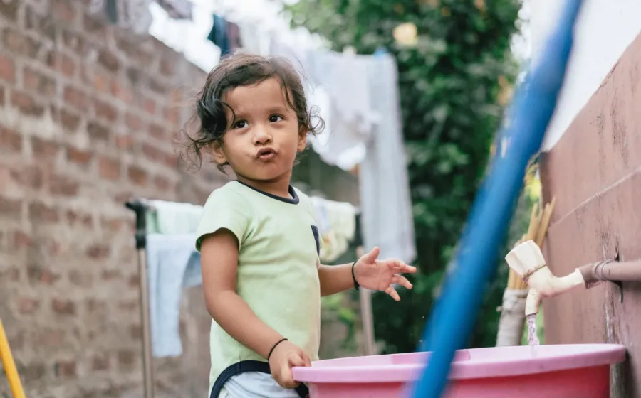Seorang anak kecil sedang merapikan mainannya sendiri di rumah sebagai bentuk cara membantu anak mandiri