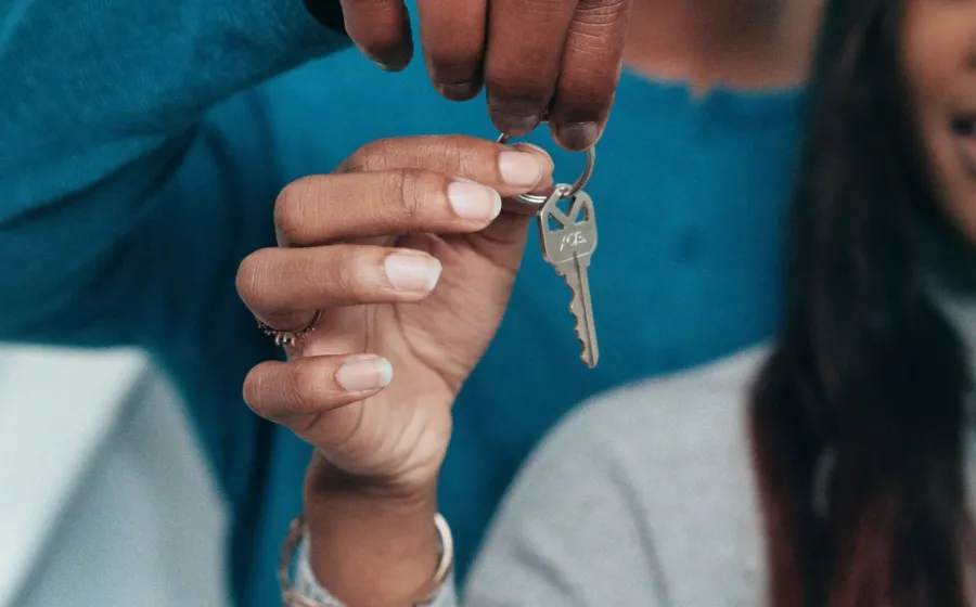 Pasangan baru menikah tersenyum bahagia memegang kunci rumah baru impian mereka