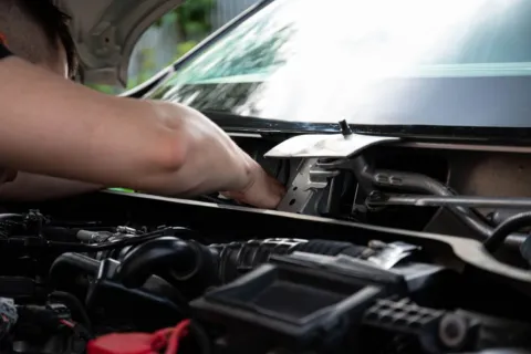 Mekanik sedang melakukan cara merawat mobil untuk perjalanan jauh di bengkel