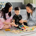 Ibu sedang melatih anak berbagi mainan dengan temannya dengan ceria dan tanpa paksaan