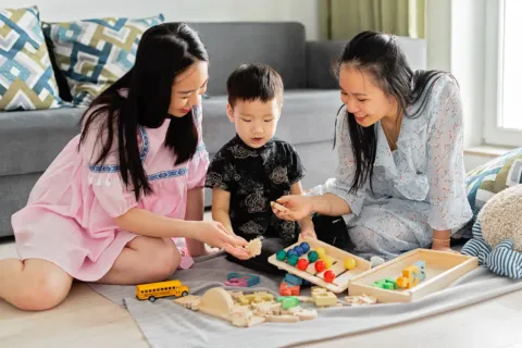 Ibu sedang melatih anak berbagi mainan dengan temannya dengan ceria dan tanpa paksaan