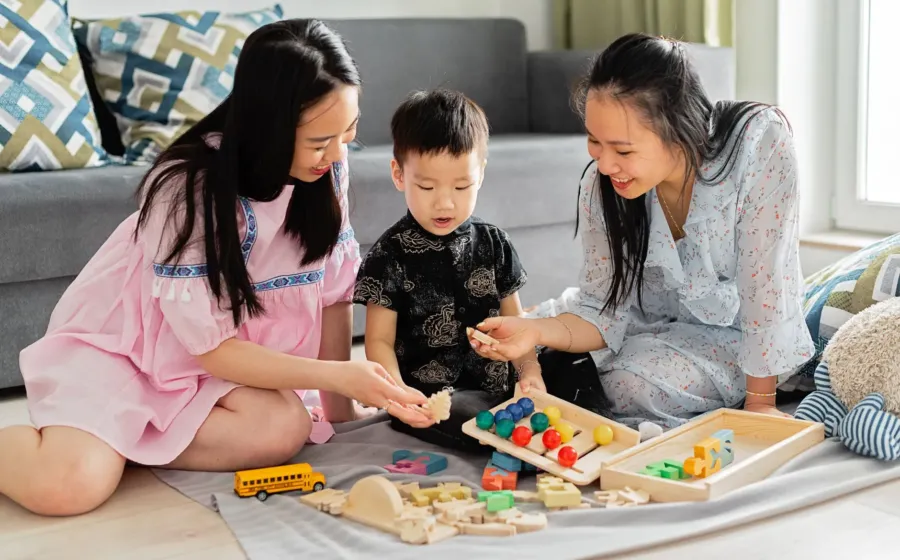 Ibu sedang melatih anak berbagi mainan dengan temannya dengan ceria dan tanpa paksaan