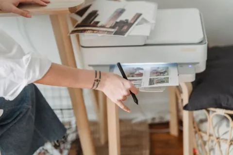 Ilustrasi printer untuk rumah tipe ink tank diletakkan di atas meja kerja yang rapi