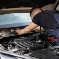 Mekanik sedang melakukan pemeriksaan mesin sebagai bagian dari tips merawat mobil berkala