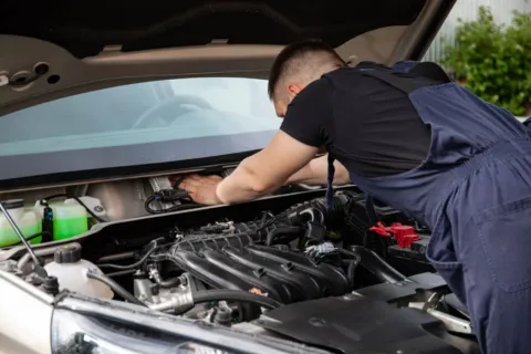 Mekanik sedang melakukan pemeriksaan mesin sebagai bagian dari tips merawat mobil berkala