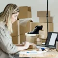 Ilustrasi cara memulai bisnis online dengan laptop dan produk jualan untuk mendapatkan cuan dari rumah