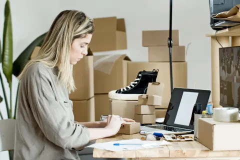 Ilustrasi cara memulai bisnis online dengan laptop dan produk jualan untuk mendapatkan cuan dari rumah