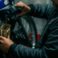 Mekanik berpengalaman sedang menuangkan cairan oli motor berkualitas ke dalam mesin motor matic untuk perawatan rutin