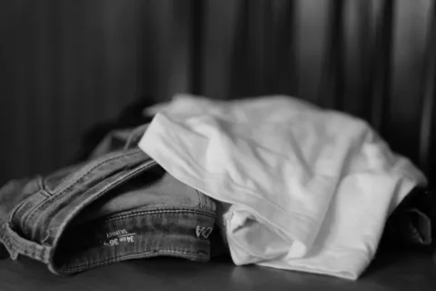 Pakaian nyaman berbahan katun dan linen yang tergantung rapi di gantungan baju kayu minimalis